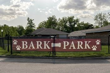 A sign that says bark park in front of houses