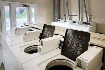 A row of washing machines in a laundromat with two chalkboards on them