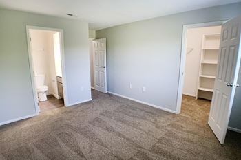 An empty living room with carpeting and a closet and a toilet