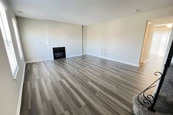 An empty living room with wood flooring and a fireplace