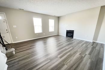 An empty living room with wooden floors and a fireplace