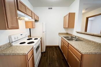 A kitchen with white appliances and granite counter tops and wooden cabinets
