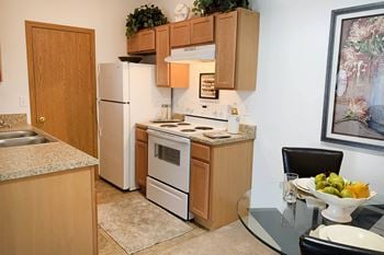 Full kitchen with white appliances and wooden cabinets and a glass table