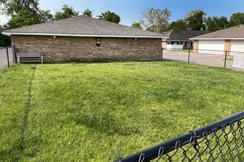 A backyard with a grassy area and a brick building in the background