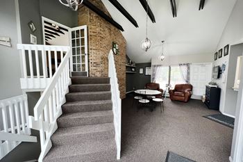 A staircase in a house with a brick wall and a white railing