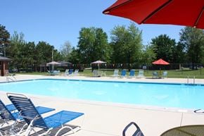 Forest Park apartment for rent - A pool with blue chairs and a red umbrella.
