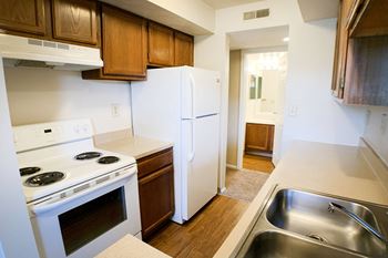 A kitchen with white appliances and wooden cabinets and a white refrigerator