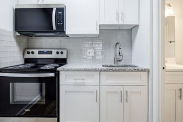 Cincinnati apartment for rent - A black microwave oven is mounted above a black stove in a kitchen.