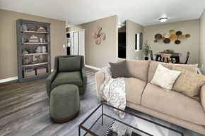 Hamilton apartment for rent - A living room with a green chair, a brown couch, and a wooden bookcase.