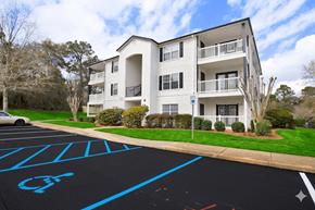 Mobile apartment for rent - A parking lot with a handicap parking space in front of a white apartment building.
