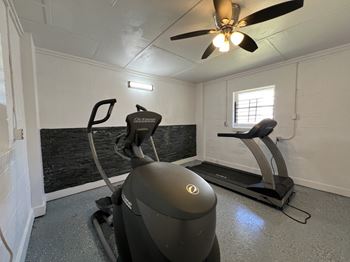 A gym with a exercise bike and a ceiling fan