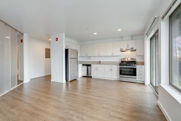 Seattle apartment for rent - a kitchen with white cabinets and stainless steel appliances and a wood floor