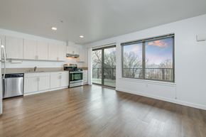 Seattle apartment for rent - an empty living room with a large window and a kitchen