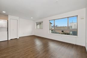 Seattle apartment for rent - an empty living room with a large window and a kitchen