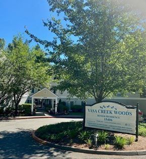 Bellevue apartment for rent - A sign for Vasa Creek Woods Senior Residence is in the foreground of a tree-lined street.