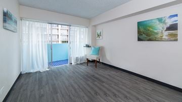 Honolulu apartment for rent - a living room with white walls and curtains and a door to a balcony