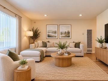 Ventura townhouse for rent - A living room with a white couch, a green cushion, a wooden coffee table, and a large window with white curtains.