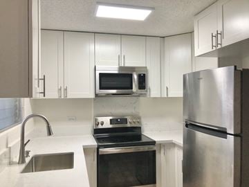 Honolulu apartment for rent - a kitchen with stainless steel appliances and white cabinets