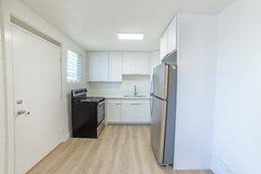Honolulu apartment for rent - A kitchen with white cabinets and a black fridge.