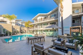 Torrance apartment for rent - a swimming pool with a table and chairs in front of a building