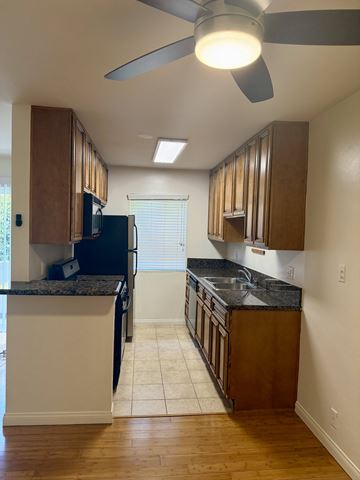 Los Angeles apartment for rent - A kitchen with a black refrigerator and wooden cabinets.
