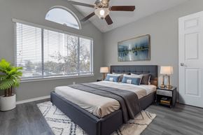 Dallas apartment for rent - A bedroom with a large bed, a ceiling fan, and a painting on the wall.