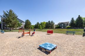 Longmont apartment for rent - A playground with a blue sandbox in the foreground and a red slide in the background.