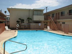 Torrance apartment for rent - A pool in a residential area with a brown fence and a building in the background.