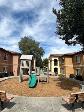 Red Bluff apartment for rent - A playground with a green slide and wooden benches.