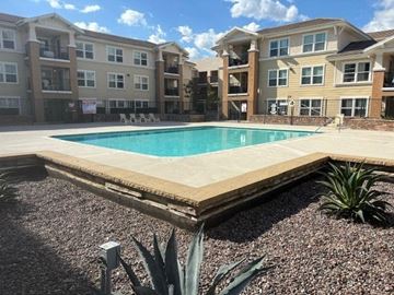 Glendora apartment for rent - A swimming pool surrounded by a fence and a building in the background.