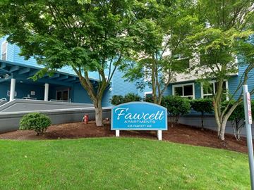 Tacoma apartment for rent - a blue and white sign in the grass in front of a building