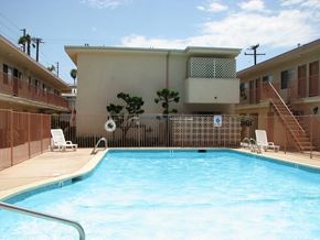 Torrance apartment for rent - A pool in front of a building with a tree in the background.