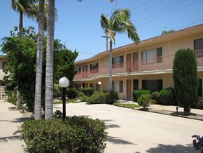 Torrance apartment for rent - A street view of a residential area with apartment buildings and palm trees.