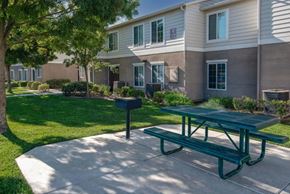 Mendota apartment for rent - A green picnic table is in front of a building with a mailbox.