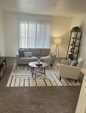Mecca apartment for rent - A living room with a grey couch, a small table, and a carpet.
