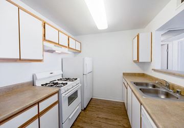 Las Vegas apartment for rent - A kitchen with white appliances and wooden cabinets.