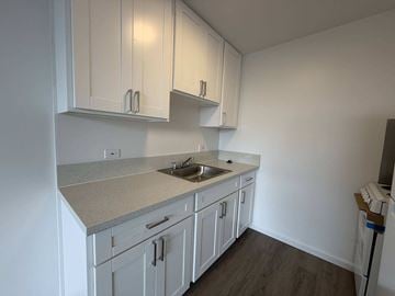 Honolulu apartment for rent - A kitchen with white cabinets and a granite countertop.