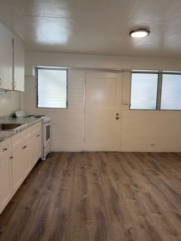 Honolulu apartment for rent - A kitchen with white cabinets and a wooden floor.