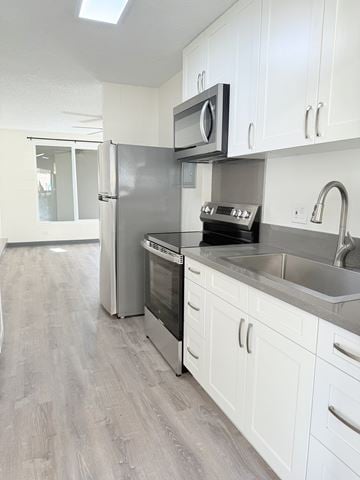 Waipahu apartment for rent - A kitchen with white cabinets and a black countertop.