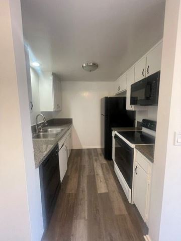 Redondo Beach apartment for rent - A kitchen with black appliances and white cabinets.