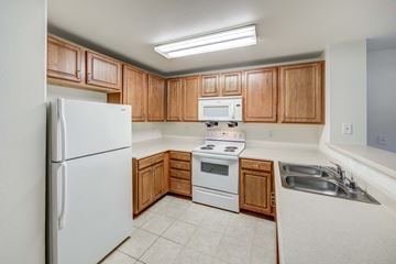 Las Vegas apartment for rent - A kitchen with wooden cabinets and white appliances.