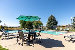 Brighton apartment for rent - A table with chairs and an umbrella is set up by a pool.