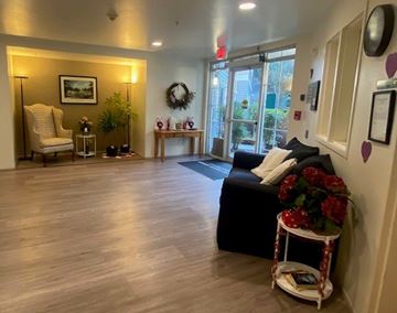 Bellevue apartment for rent - A living room with a black couch, a chair, a table with a plant, and a wreath on the wall.