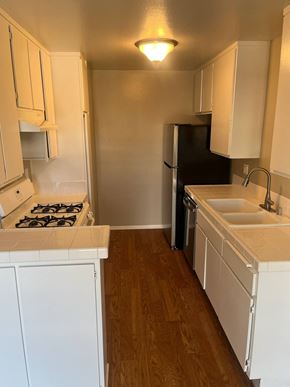 Los Angeles apartment for rent - A kitchen with a black refrigerator and white cabinets.