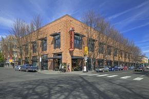 Portland apartment for rent - A red brick building with a yellow awning sits at a street corner.
