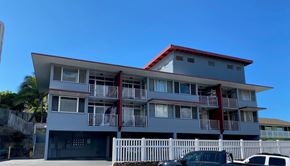 Wailuku apartment for rent - A grey building with a red roof and white fence.