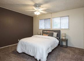 Austin apartment for rent - A bedroom with a bed, pillows, a nightstand, and a ceiling fan.
