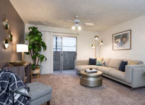 Austin apartment for rent - A living room with a grey sofa, a wooden side table, and a ceiling fan.