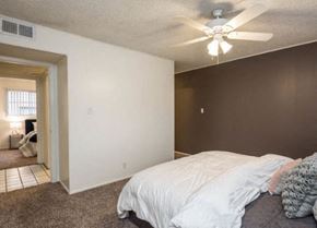 Austin apartment for rent - A bedroom with a bed, ceiling fan, and a doorway leading to another room.