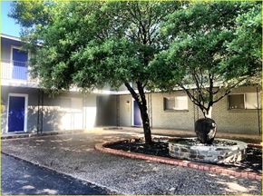 Austin apartment for rent - A tree in front of a building with a round planter.